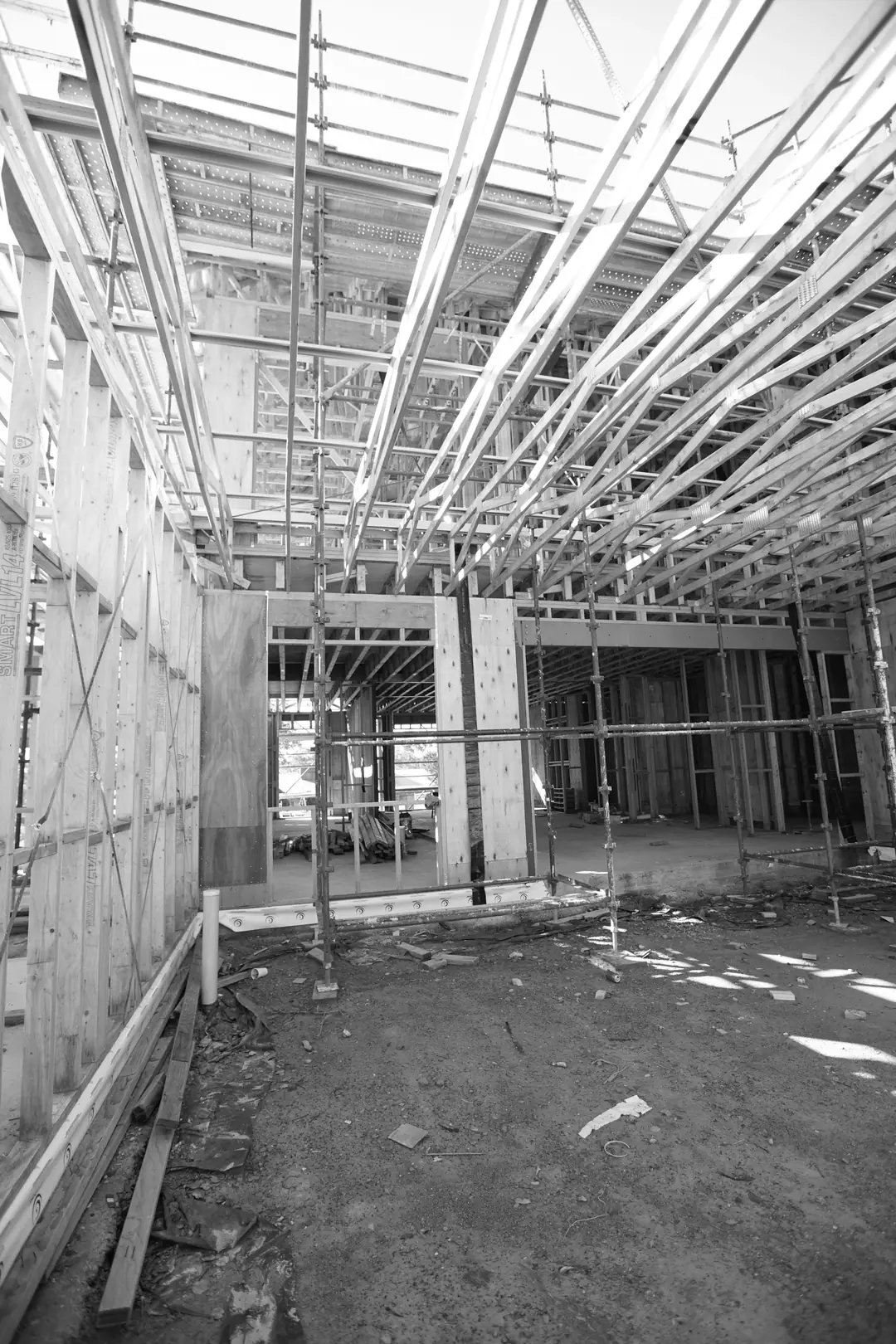 Timber wall frames and floor joists inside a building under construction, viewed upward